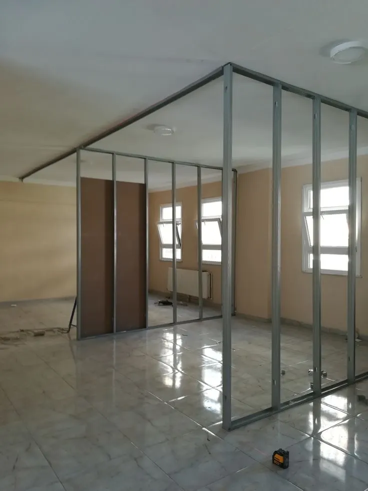 Metal stud frame for a room partition, with gypsum boards going up alongside Metal stud frame for a room partition, with gypsum boards going up alongside
